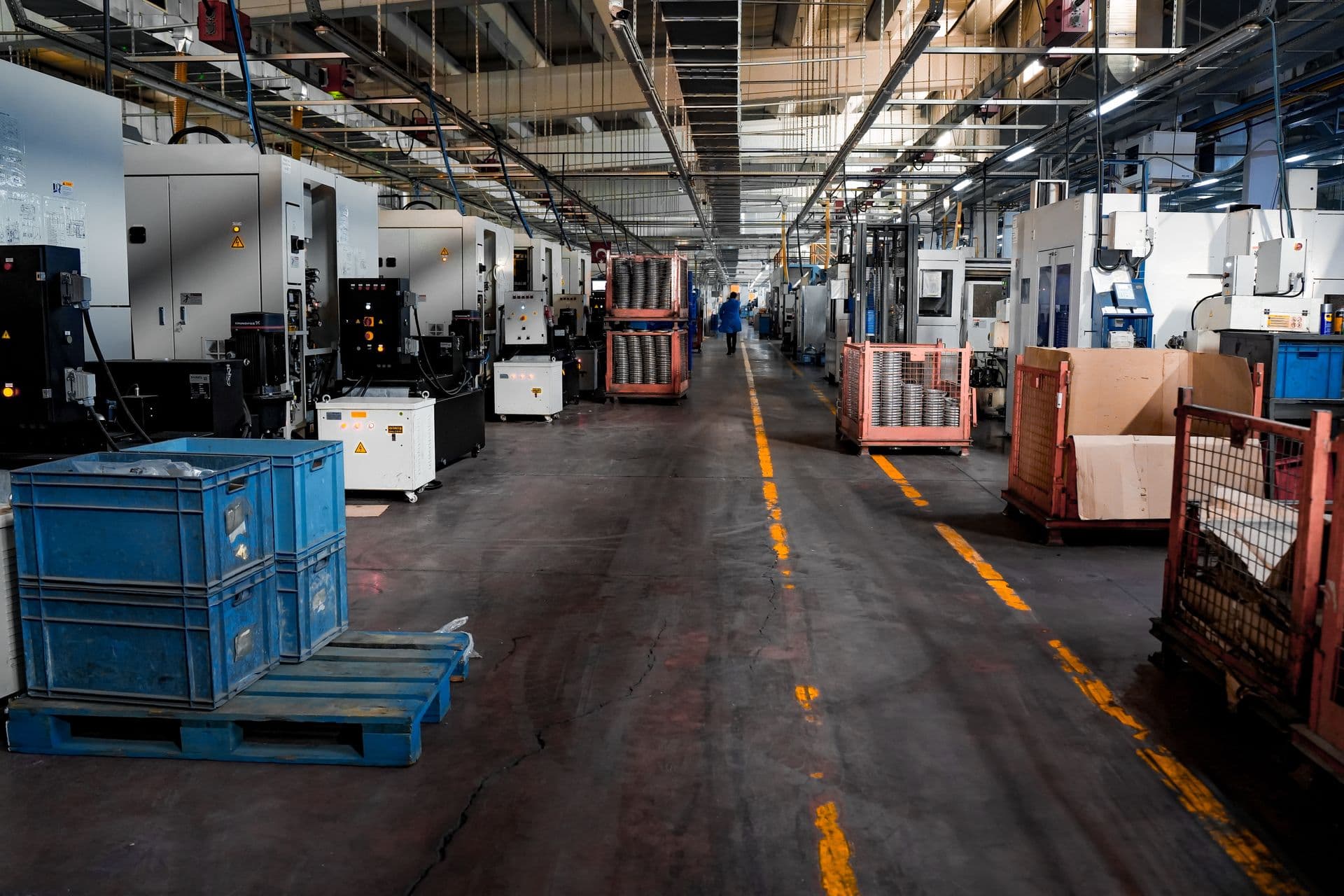 Industrial factory floor with rows of CNC machining centers and material handling equipment.